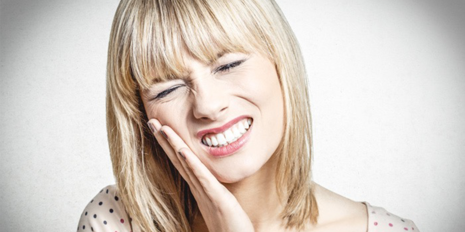 痛みに顔を歪ませ頬をおさえる女性