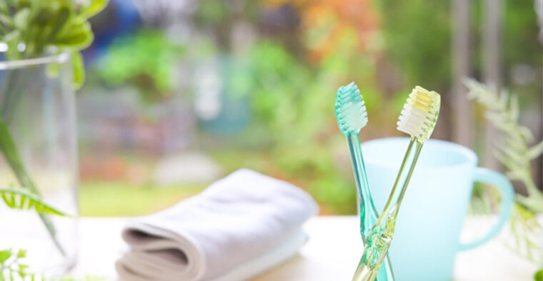 2本の歯ブラシとコップ・畳まれたタオルの写真