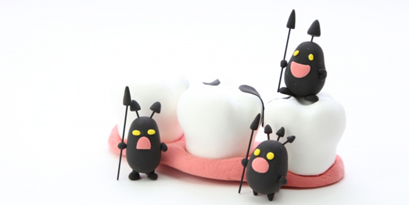 汚れた歯の模型に虫歯菌が集まっているイメージ