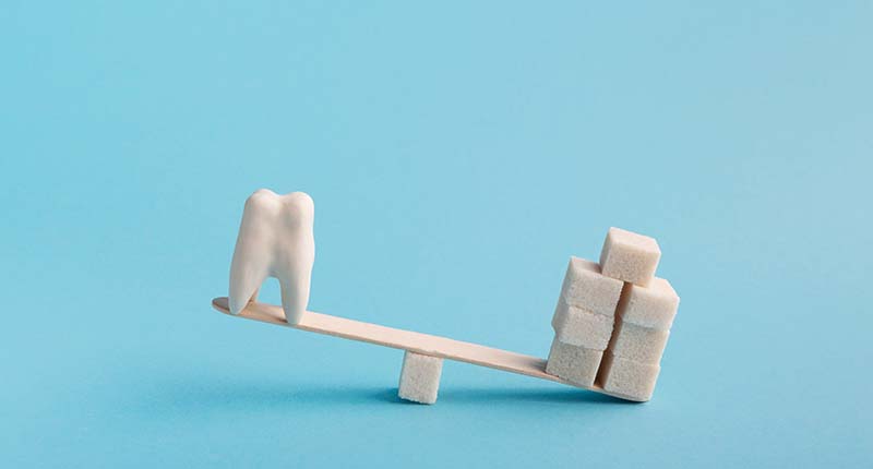 歯と角砂糖が乗り、角砂糖に傾くシーソー