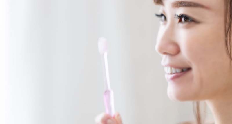 歯ブラシを持ち、微笑む女性