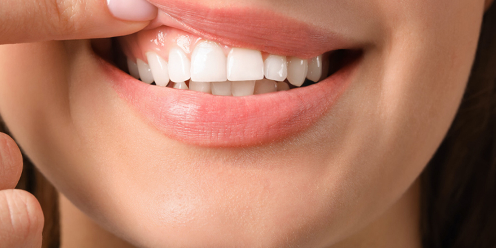 唇を指で押さえ、真っ白な綺麗な歯を見せる女性