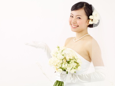 ウエディングドレス姿で微笑みながら、手で奥を示す女性