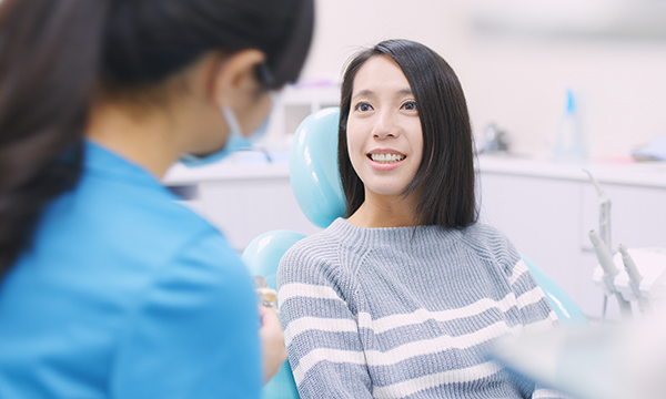 歯科医院スタッフに説明を受ける女性