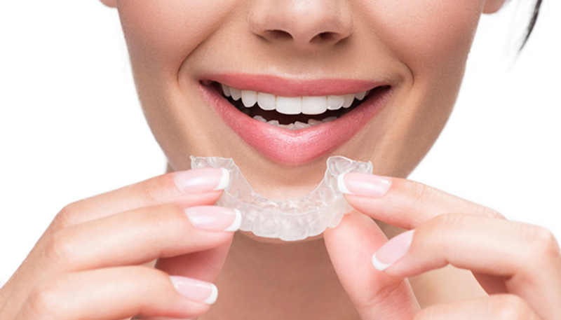 透明なマウスピースを口元に近づけている様子