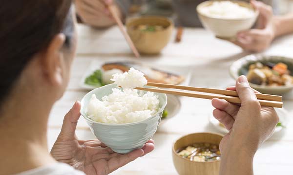 お米を箸で口まで運ぼうとしている食事中の女性の様子