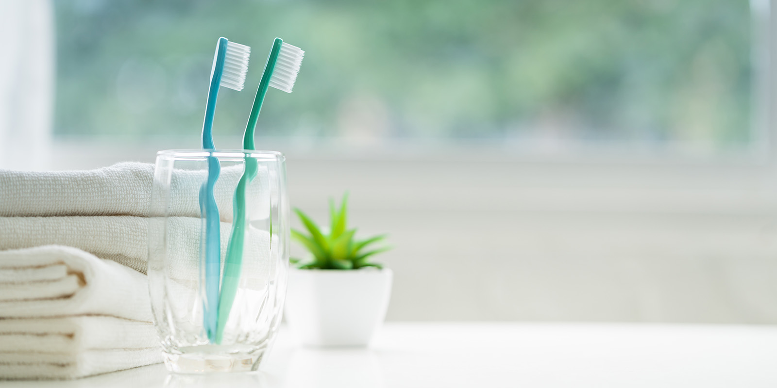 コップに入った歯ブラシ2本とタオルの写真