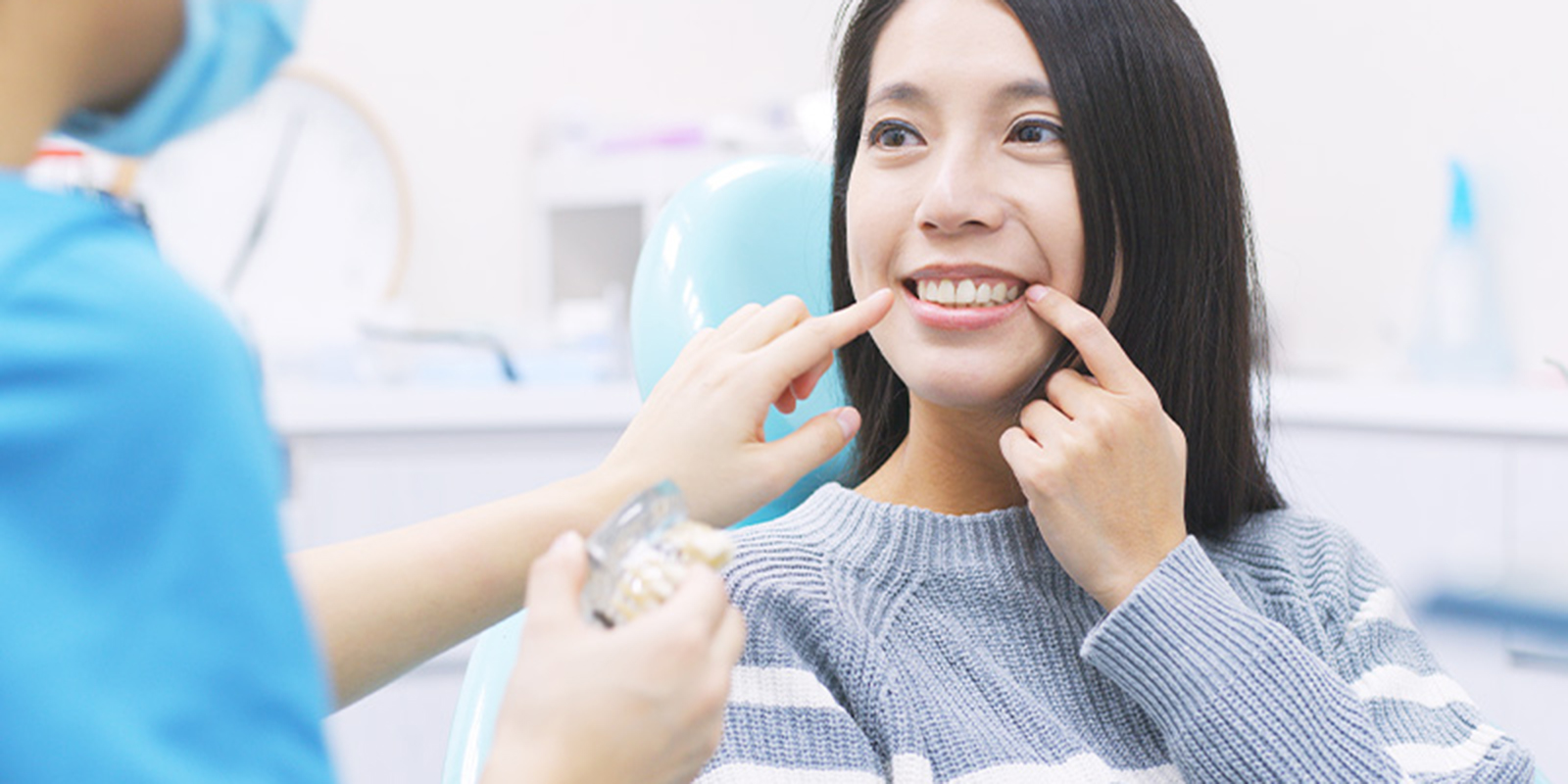 歯科医院スタッフに説明を受け、自分の歯を指さす女性