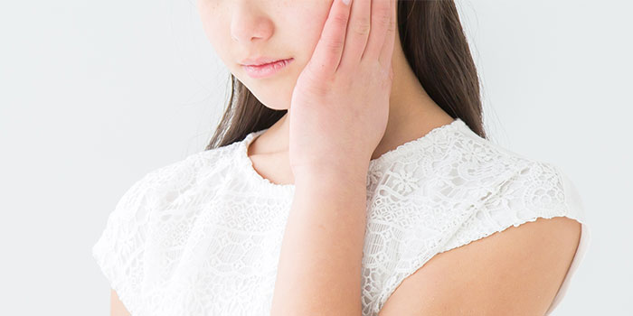 頬をおさえる女性